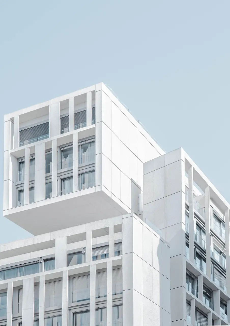 Modern white residential condo building with stacked balconies against a pale sky